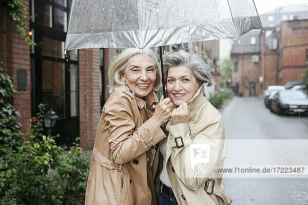 Fröhliche Frauen unter Regenschirm genießen den Regentag