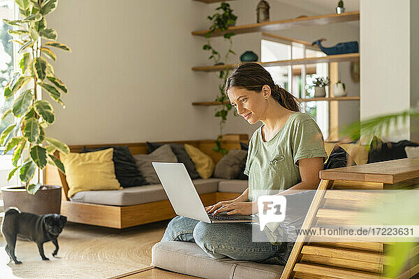 Female entrepreneur using laptop while sitting on sofa at home