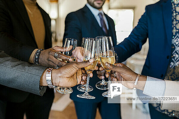 Hände von eleganten Männern  die bei einem Bankett mit Champagner anstoßen