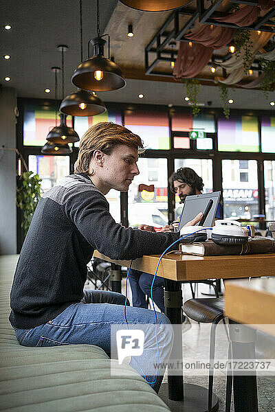 Männlicher Unternehmer sitzt am Schreibtisch und benutzt sein Smartphone in einem Coworking-Büro