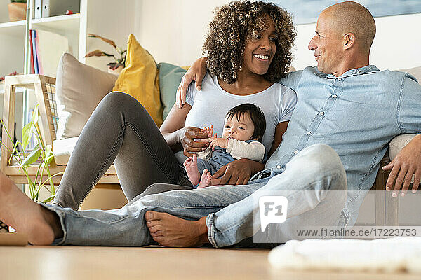 Happy family with daughter sitting on floor in living room