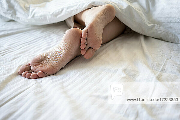 Junge Frau Beine in Decke auf Bett zu Hause