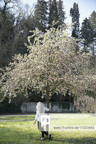 Mature woman walking around tree during springtime