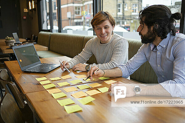 Smiling businessman brainstorming with male colleague while working in office