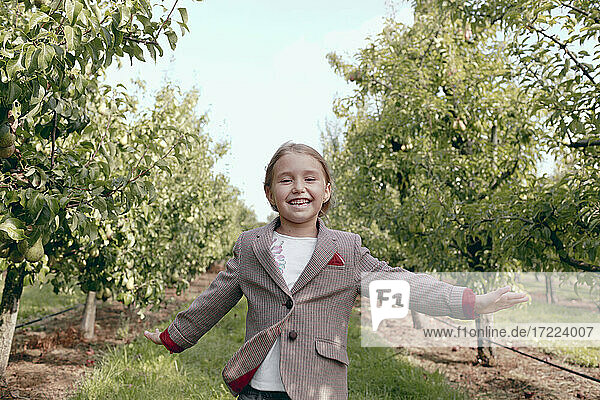 Fröhliches Mädchen läuft im Obstgarten