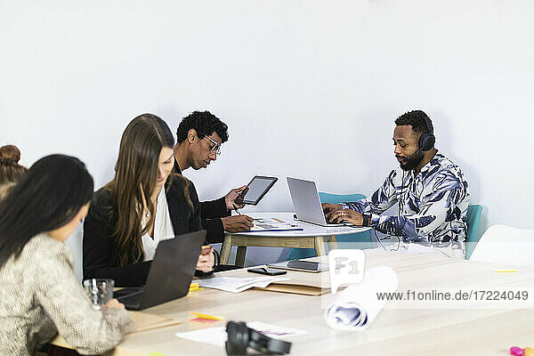 Businessmen working while sitting with colleagues in creative office