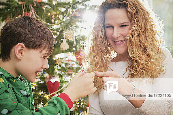 Glückliche Mutter und Sohn halten einen Wunschknochen mit einem Weihnachtsbaum im Hintergrund