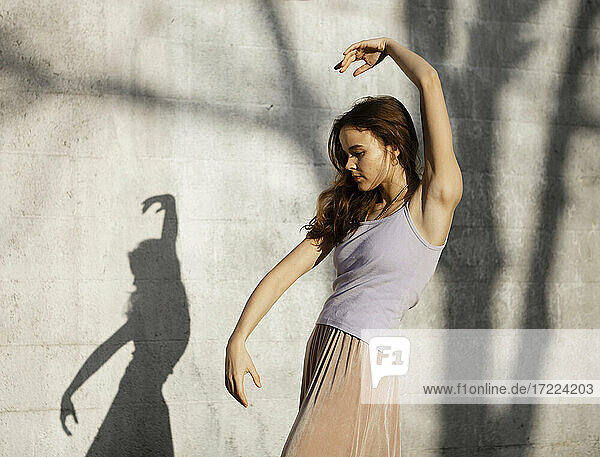 Schöne junge Frau tanzt an der Wand während eines sonnigen Tages