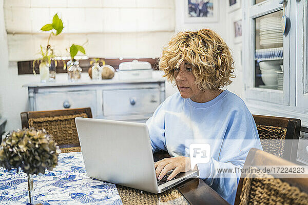 Reife Frau arbeitet am Laptop  während sie zu Hause sitzt