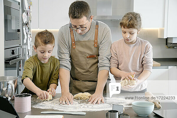 Mann und Kinder bereiten gemeinsam in der Küche Essen zu