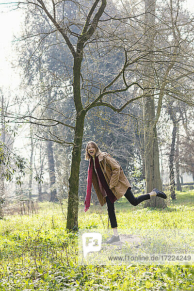 Carefree woman standing on tree stump at park