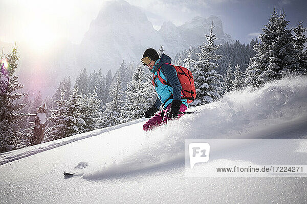 Female skier skiing on snowy mountain during sunny day