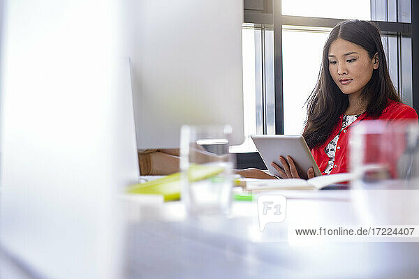 Konzentrierte Geschäftsfrau  die ein digitales Tablet benutzt  während sie im Büro sitzt