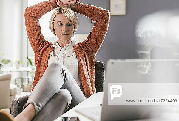 Mature female professional watching laptop while working at home