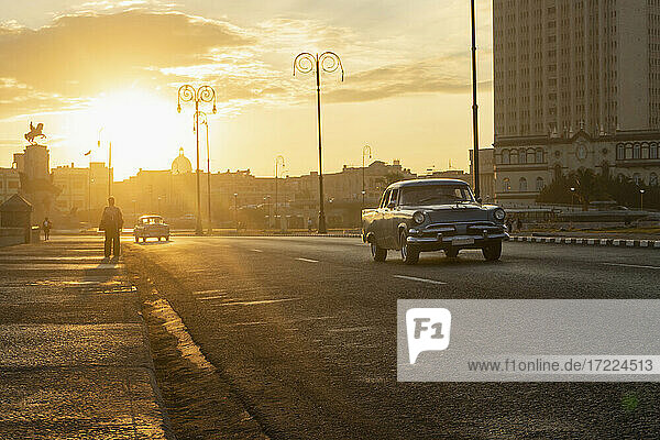 Autos auf der Straße in der Stadt bei Sonnenuntergang