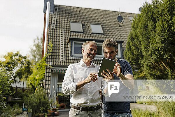 Glücklicher Vater und Sohn benutzen ein digitales Tablet  während sie im Hinterhof stehen