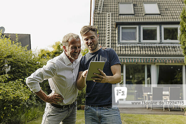Sohn zeigt seinem Vater ein digitales Tablet im Hinterhof