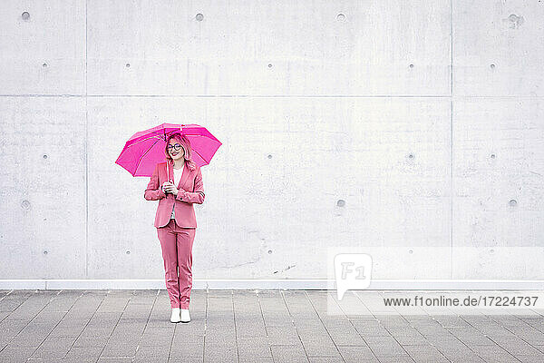 Junge Frau mit Regenschirm auf dem Fußweg stehend