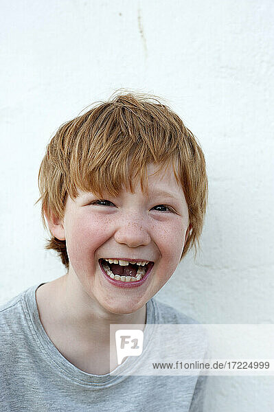 Laughing redhead boy in front of white wall