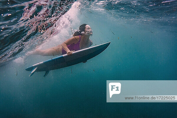 Female surfing on surfboard underwater