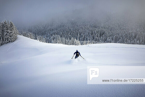 Mittlerer erwachsener Mann beim Skifahren auf einem schneebedeckten Berg im Winter