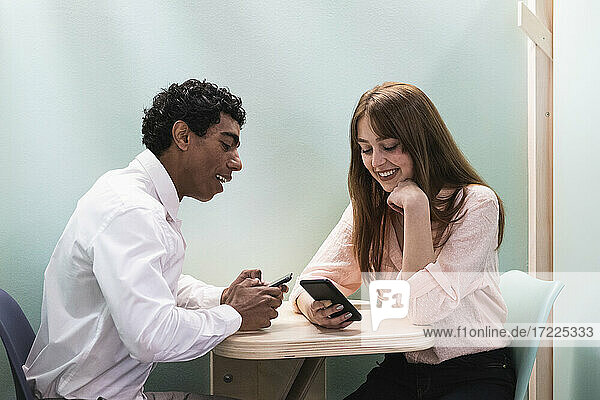 Lächelnde Geschäftsleute mit Mobiltelefonen in einer Cafeteria