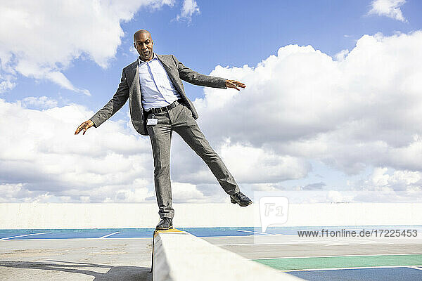 Geschäftsmann balanciert auf einer Stützmauer am Terrassenparkplatz