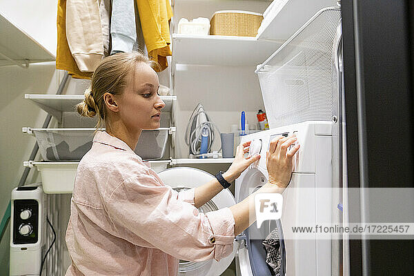 Frau benutzt Waschmaschine im Hauswirtschaftsraum