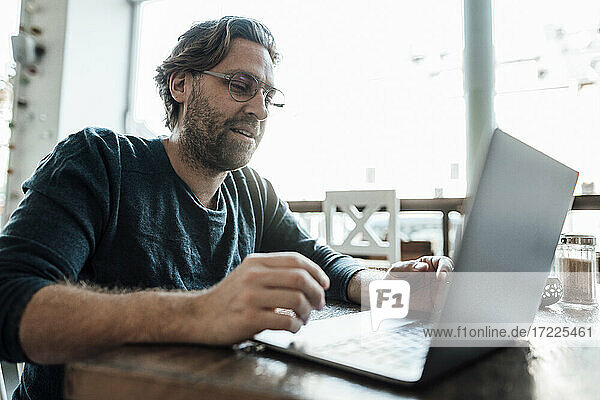 Mann benutzt Laptop in einem Kaffeehaus