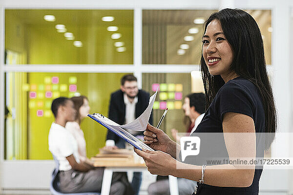 Junge Unternehmerin mit Dokument lächelnd im Büro