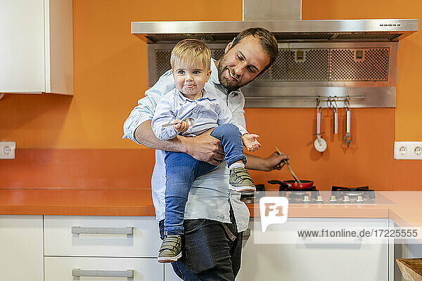 Vater trägt seinen Sohn bei der Zubereitung von Speisen in der Küche