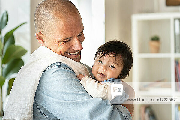 Glücklicher Vater betrachtet lächelnd süßes Baby zu Hause