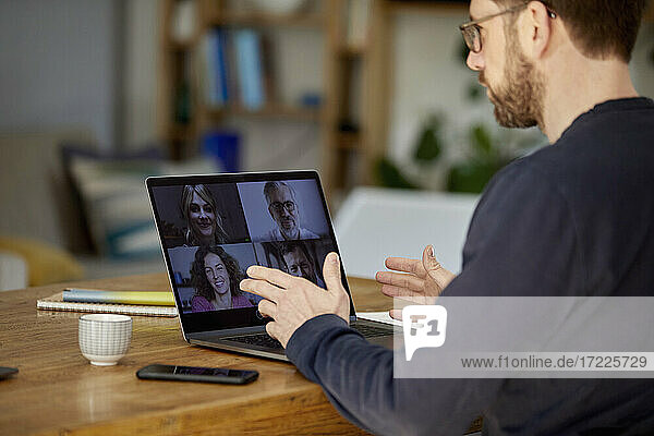 Mature businessman discussing with colleagues on video call through laptop over table