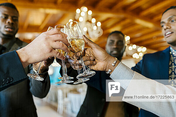 Hands of male friends toasting champagne at banquet