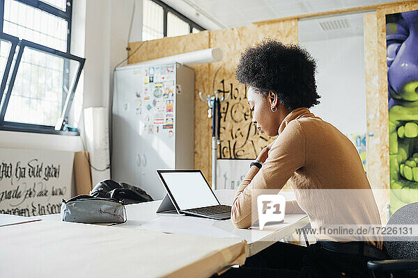Junge Frau mit Laptop bei der Arbeit im Studio