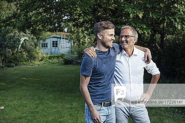 Father and son with arms around standing in backyard