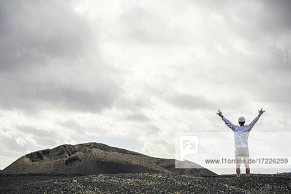 Male tourist with arms outstretched standing at volcanic landscape