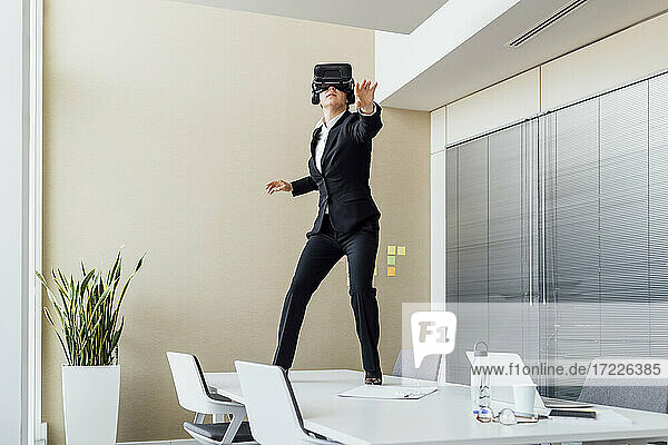 Frau benutzt ein Virtual-Reality-Headset  während sie auf einem Konferenztisch im Büro steht
