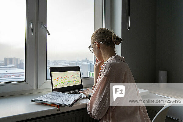 Frau arbeitet am Laptop  während sie zu Hause im Büro sitzt