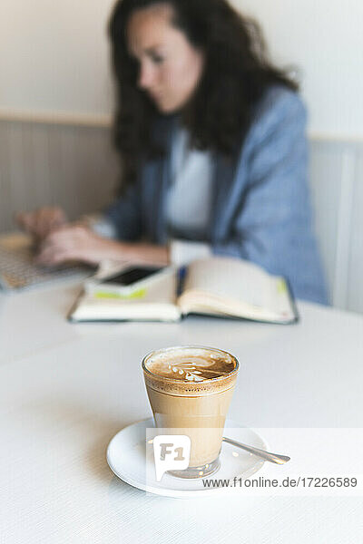 Kaffee auf dem Tisch  während eine Geschäftsfrau in einem Café arbeitet