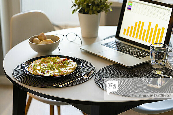 Daten über Laptop-Bildschirm und Essen auf dem Tisch zu Hause