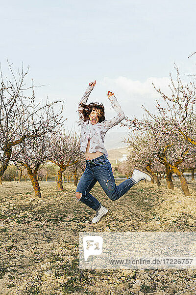 Unbekümmerte junge Frau  die auf Mandelbäume springt