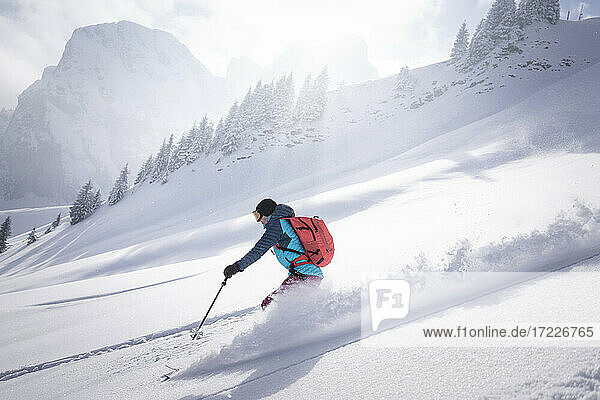 Mittlere erwachsene Frau beim Skifahren auf einem schneebedeckten Berg an einem sonnigen Tag