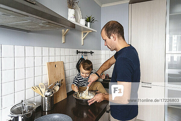 Vater mit Sohn bei der Essenszubereitung in der Küche