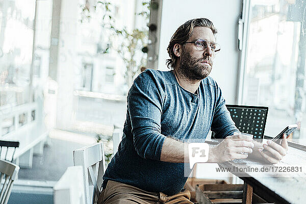 Mann mit Kaffeetasse am Laptop in einem Café sitzend