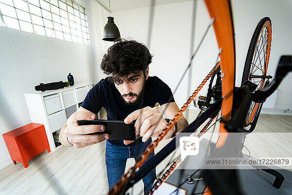 Junger Mann fotografiert zu Hause sein Fahrrad mit dem Smartphone