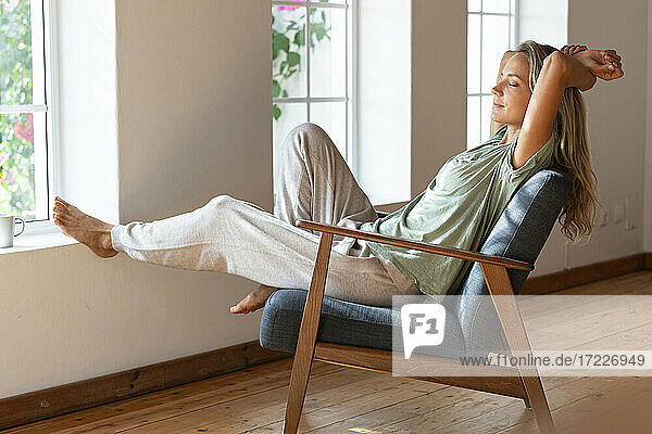 Woman with eyes closed resting on armchair at home