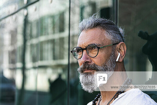 Hipster-Mann mit In-Ear-Kopfhörern schaut weg