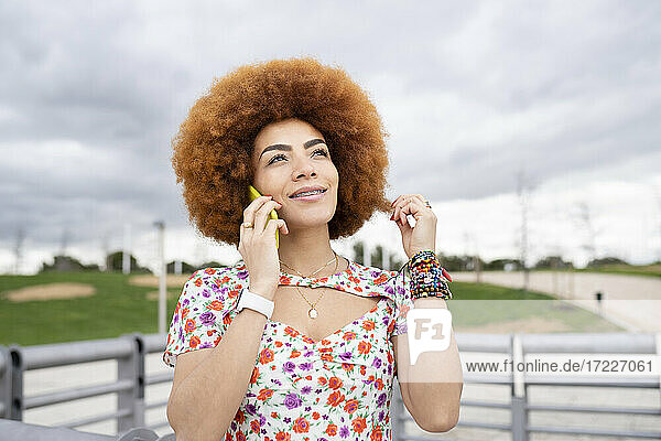 Lächelnde Frau  die im Park mit einem Mobiltelefon spricht