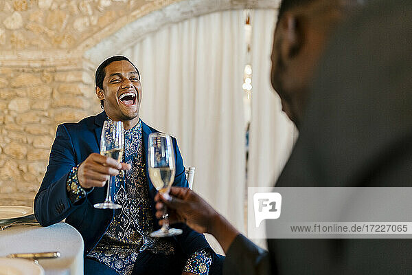 Eleganter Mann lachend und mit Champagner in der Hand beim Bankett
